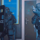A Ready or Not screenshot depicting two SWAT team members equipped with tactical gear shooting through some room.